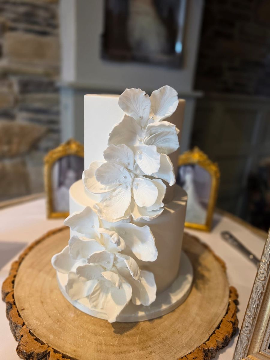 Two tier white wedding cake with a cascade of sugar petals