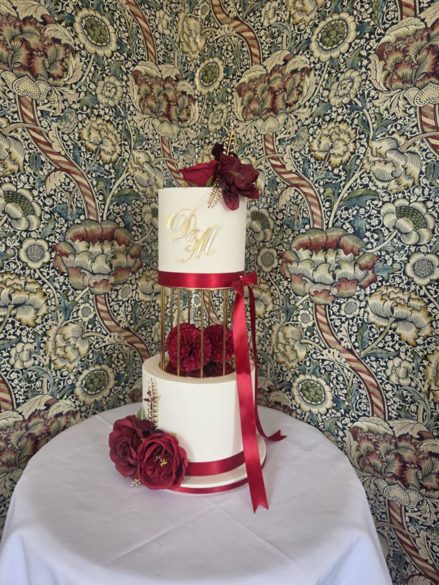 Ivory wedding cake with burgundy roses, satin ribbon and a separated tier